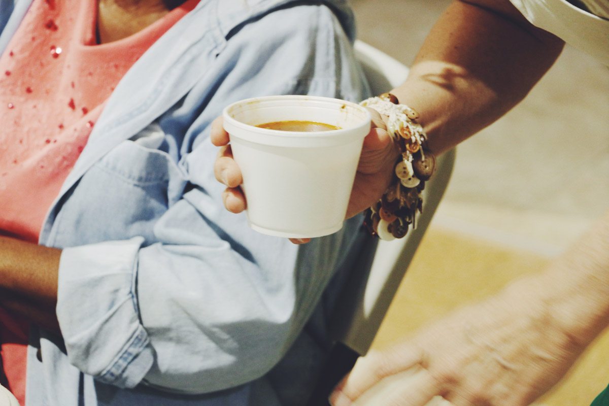 A guest cradling a warm cup of soup in both hands